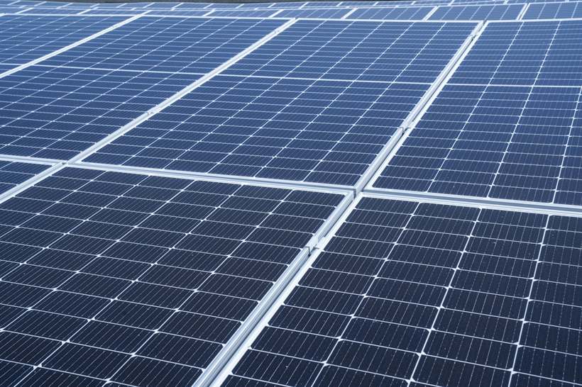 Grande conjunto de módulos fotovoltaicos alinhados em cobertura industrial
